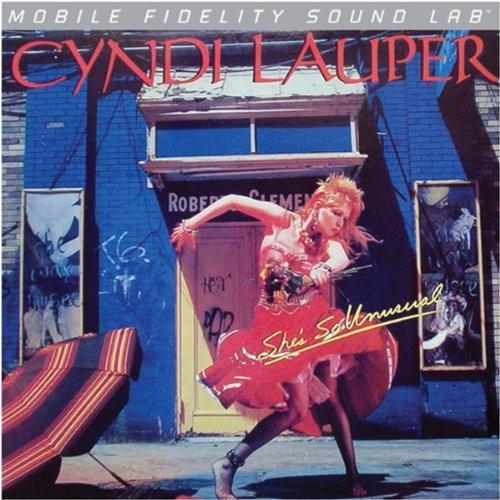 Vinyl record cover featuring a woman in a red dress posing in front of a blue building