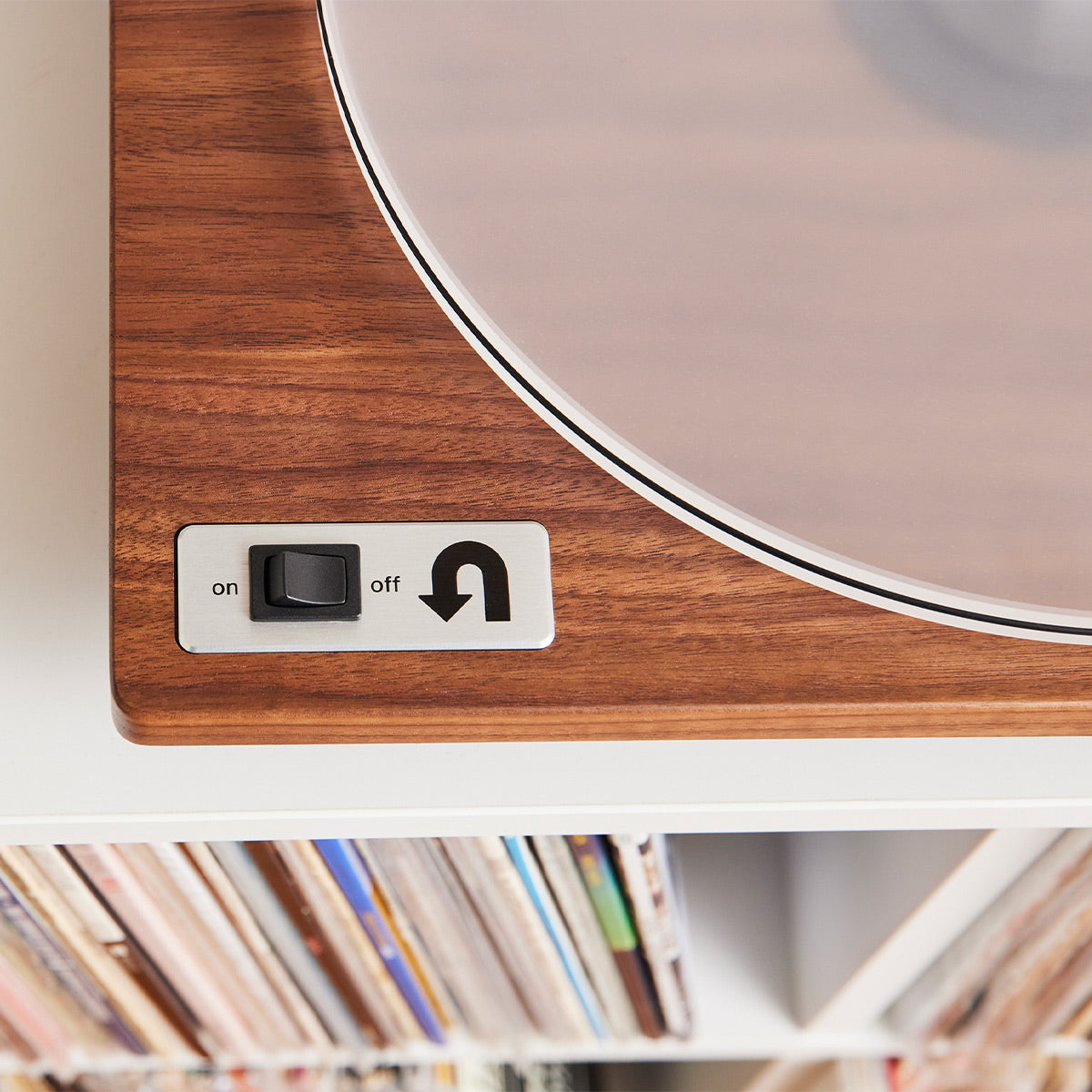 Walnut wood turntable base with a silver on/off switch and a clear acrylic platter edge