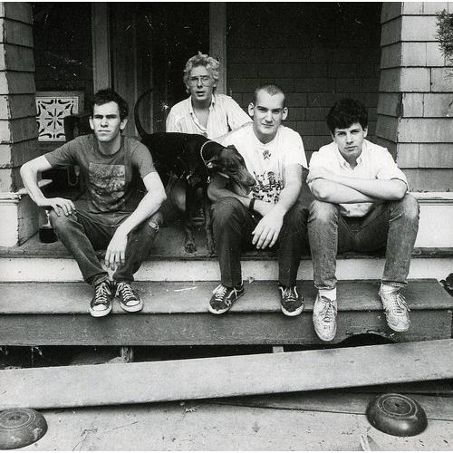 Black and white photo of four young men and a woman sitting on porch steps with a dog