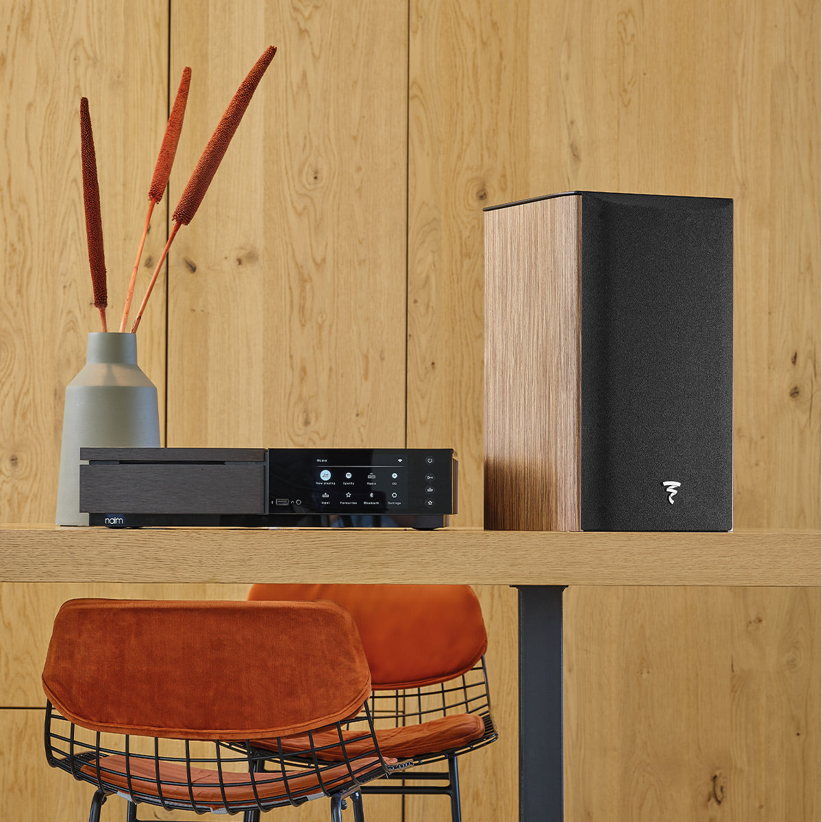 Walnut wood bookshelf speaker with black fabric grille and white logo