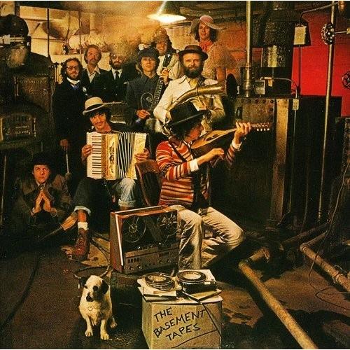 Group of musicians in a basement with instruments and a reel-to-reel tape recorder