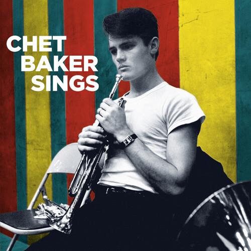 Black and white portrait of a man holding a trumpet against a colorful striped background