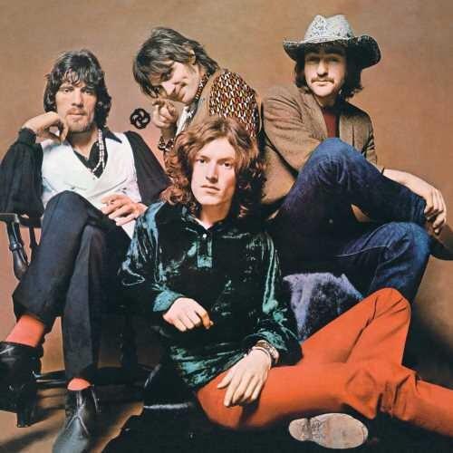 Four men in 1970s attire posing for a group portrait