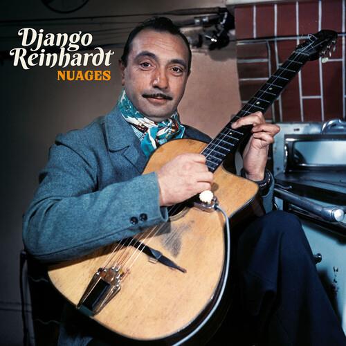 Man in a gray suit and patterned scarf playing a light wood acoustic guitar