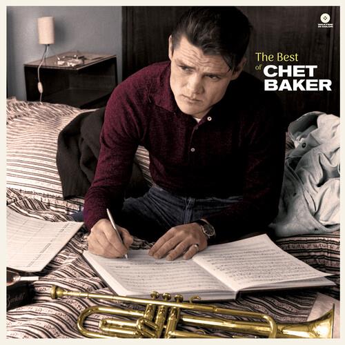 Man in maroon shirt writing in notebook with trumpet on bed