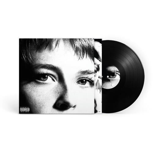 Black vinyl record partially removed from sleeve featuring a black and white close-up portrait