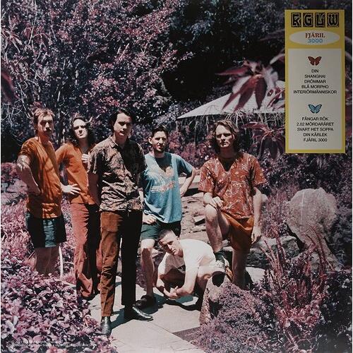 Six men in colorful patterned shirts posing in a lush garden setting