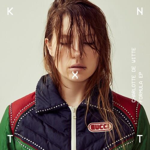 Portrait of a woman with wet hair wearing a navy blue quilted vest with red and green accents