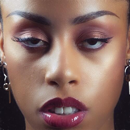 Close-up portrait of a woman with burgundy eyeshadow and glossy dark red lips