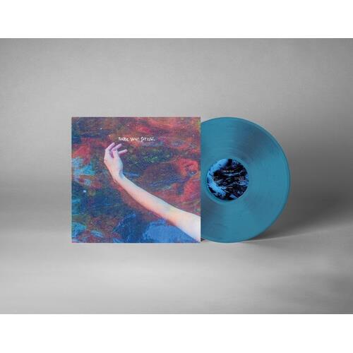 Translucent sea blue vinyl record leaning against a colorful album sleeve featuring an outstretched