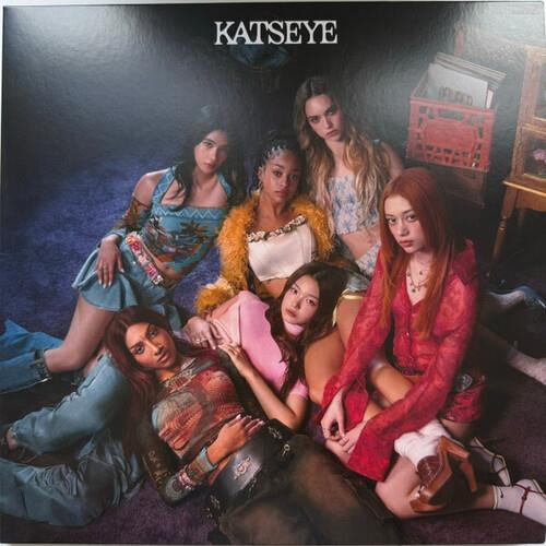 Six women posing together in colorful eclectic outfits on a dark background