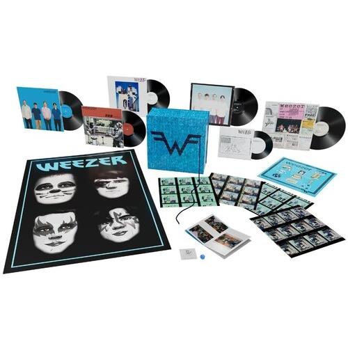 Deluxe vinyl box set with multiple LPs, singles, and a large black poster featuring four illustrated