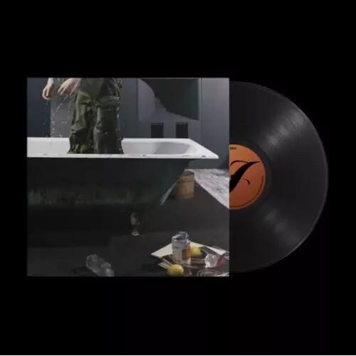 Vinyl record with orange center label next to album cover showing a person in a bathtub