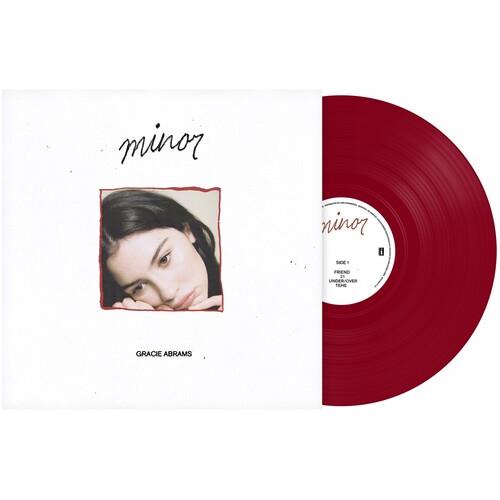 Red translucent vinyl record partially removed from white sleeve featuring a portrait of a woman