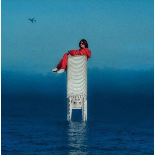 Woman in red outfit sitting atop a tall white wicker chair in the ocean