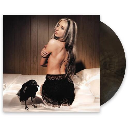 Woman with long hair sitting on a bed with a black bird