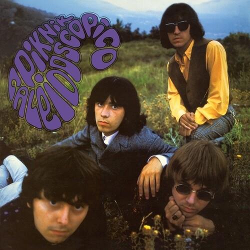 Four men posing outdoors in a grassy field with purple psychedelic text overlay