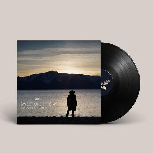 Vinyl LP sleeve showing a silhouette of a person by a lake at sunset with mountains in the backgroun