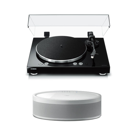 Black turntable with clear dust cover and white wireless speaker with fabric grille