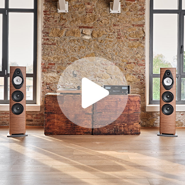 Walnut floorstanding speakers flanking a vintage wooden console with a turntable and amplifier