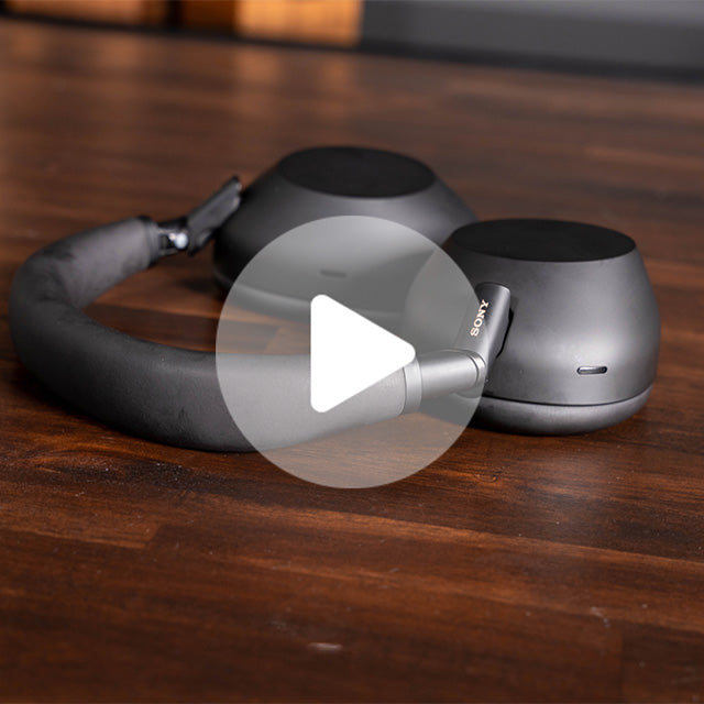 Black Sony over-ear headphones with padded headband resting on a wooden surface