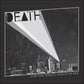 Black and white album cover with a spotlight beam over a city skyline