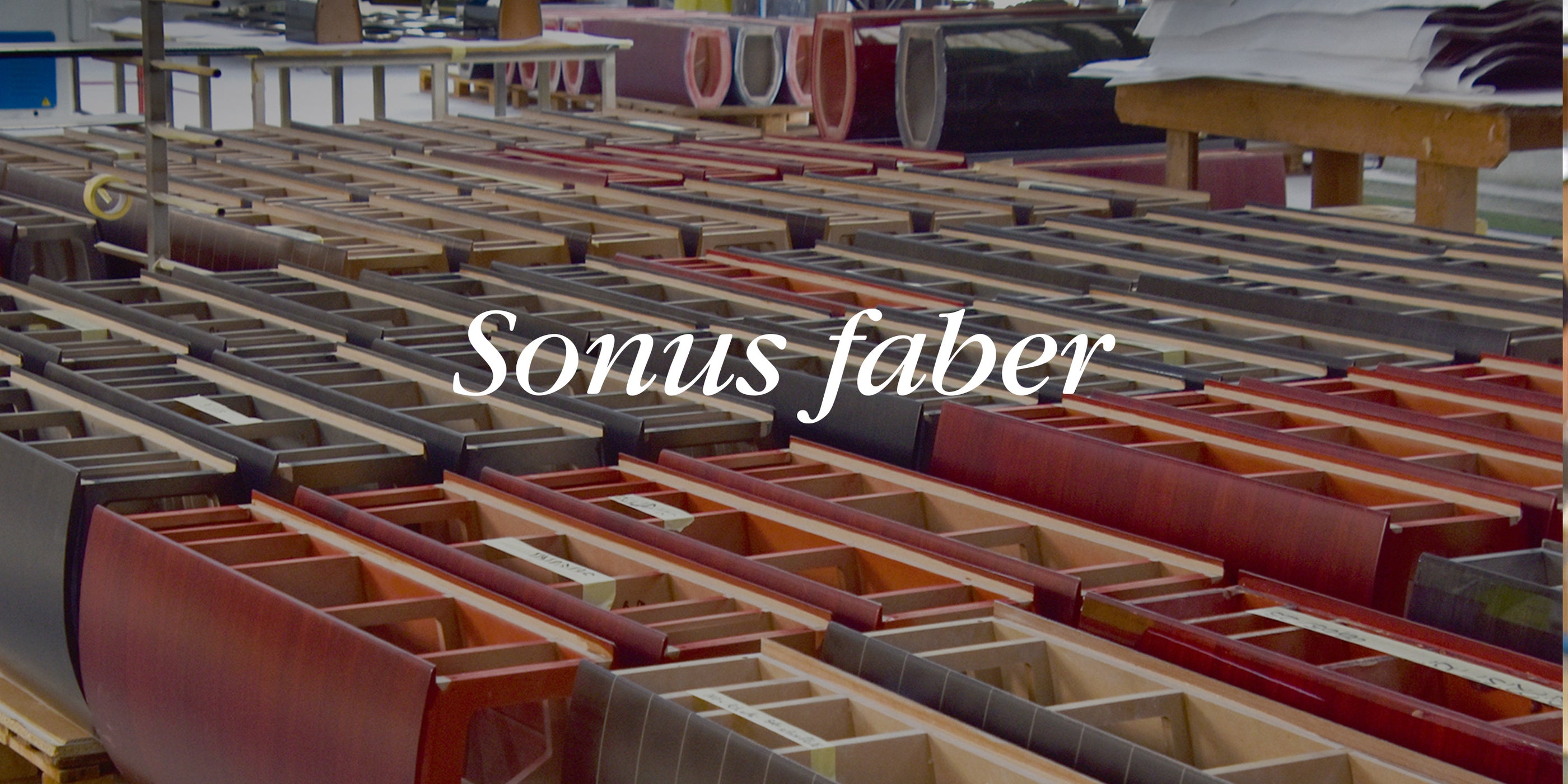 Rows of wooden speaker cabinet frames in red and black finishes on a factory floor