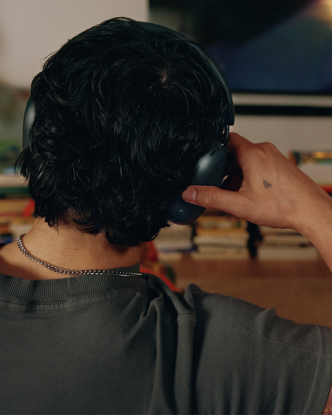 Close-up from behind of a man wearing the Sonos Ace Ultra headphones, adjusting the ear cup