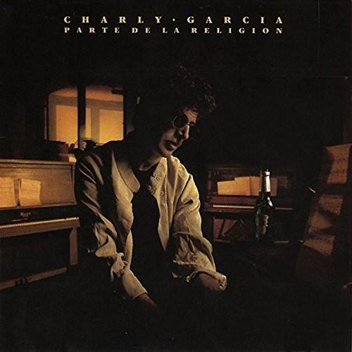 Vinyl LP cover featuring a man in sunglasses and a light jacket seated in a dimly lit room with a pi