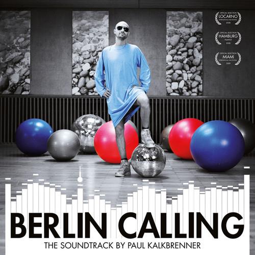 Man in blue outfit standing among colorful exercise balls and disco balls