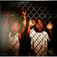 Vinyl LP cover art featuring two figures behind a chain-link fence with glowing eyes