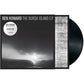 Black vinyl record partially removed from a black and white album sleeve featuring a coastal landsca