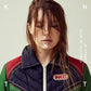 Portrait of a woman with wet hair wearing a navy blue quilted vest with red and green accents