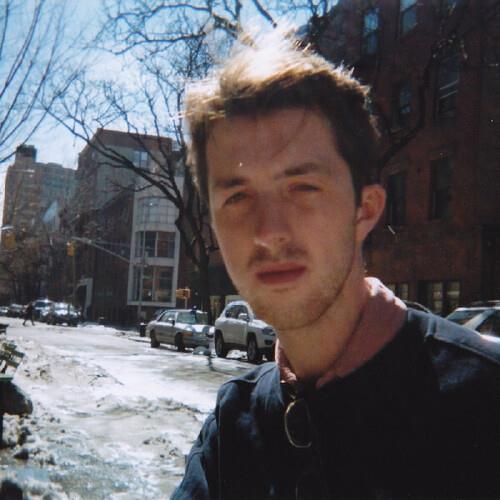 Portrait of a man on a snowy city street with bare trees and parked cars