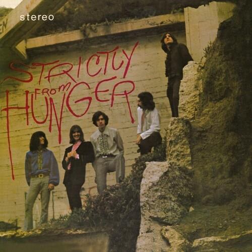 Vintage rock album cover featuring five band members posing near a concrete wall with red graffiti t