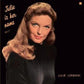 Portrait of a woman with wavy brown hair wearing a black turtleneck on a dark album cover