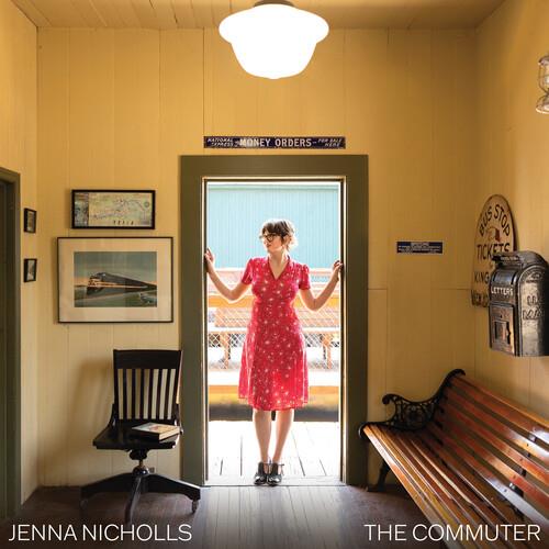 Woman in red polka dot dress standing in vintage train station doorway