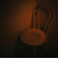 Dimly lit wooden chair with a curved backrest and round seat in a dark room