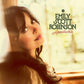 Portrait of a woman with dark hair looking upward near a window with green text overlay