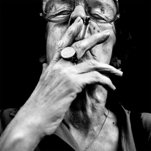 Black and white portrait of a person wearing glasses with a hand covering their mouth