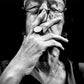Black and white portrait of a person wearing glasses with a hand covering their mouth