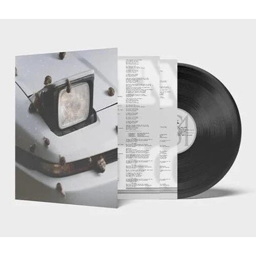 Vinyl record with white sleeve featuring a close-up of a vintage car headlight and black bumper
