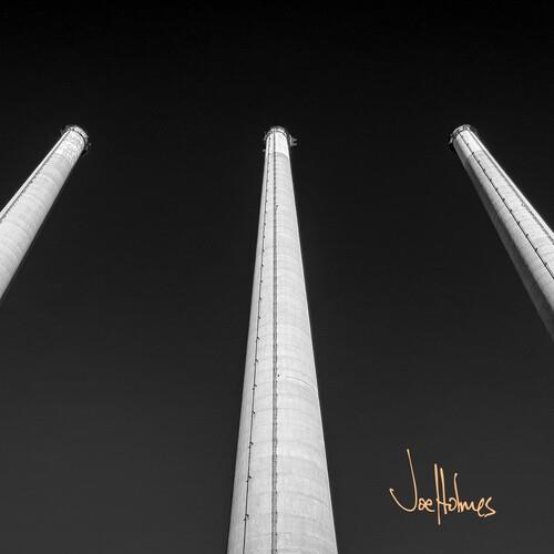 Black and white vinyl album cover featuring three tall industrial smokestacks against a dark sky