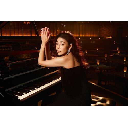 Woman in black dress seated at grand piano in dimly lit lounge