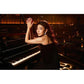 Woman in black dress seated at grand piano in dimly lit lounge
