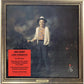 Framed album cover art featuring a man in a hat and cardigan standing in a garden setting