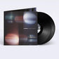 Black vinyl record partially removed from a dark gatefold sleeve with abstract blurred light pattern