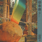 Surreal album cover art featuring a large stone sphere and a rainbow gradient beam in a ruined class