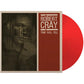 Translucent red colored vinyl record partially removed from a beige and red album sleeve featuring a