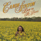 Woman standing in a field of yellow flowers with stylized text above